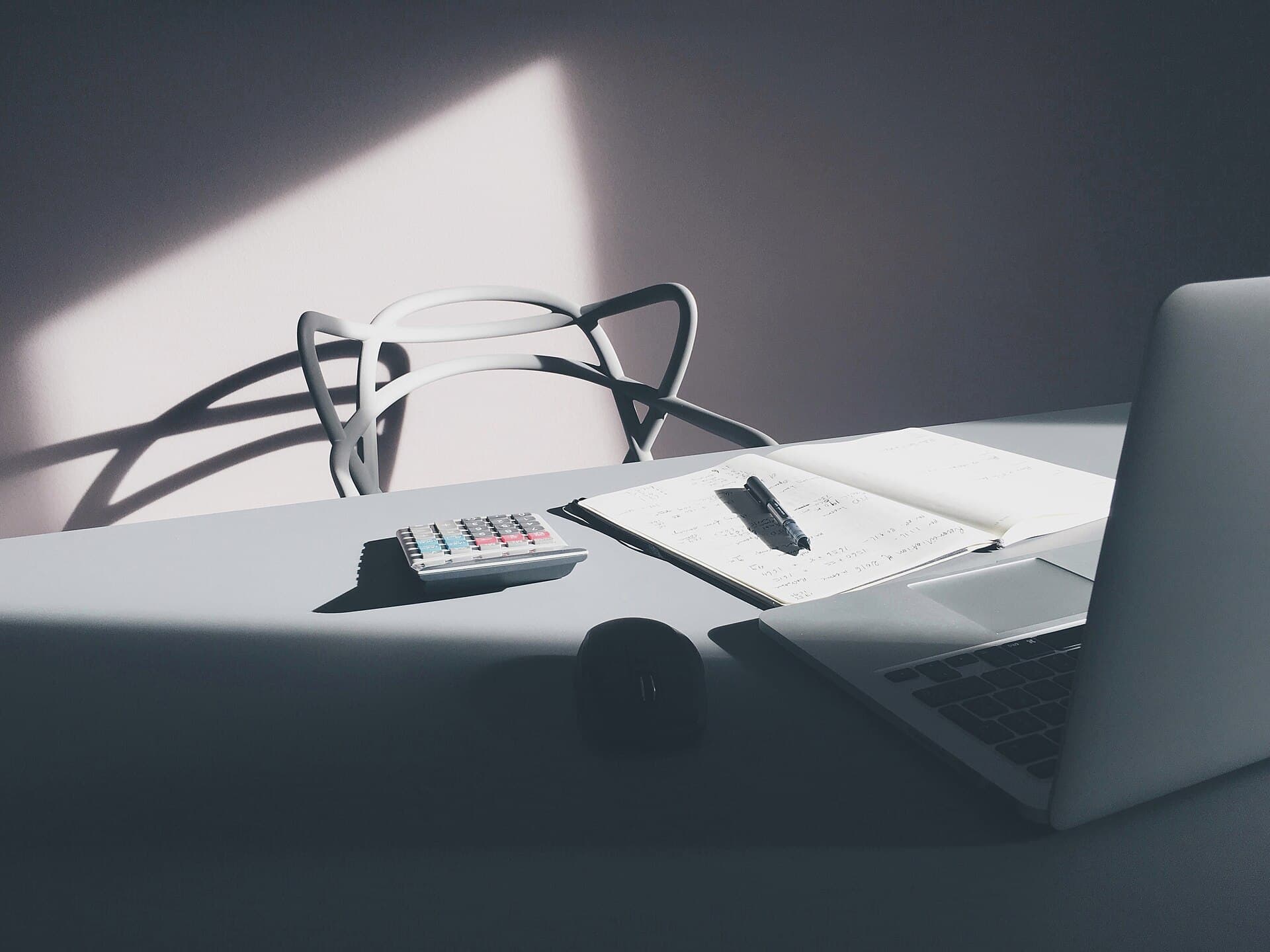 Desk with a laptop, calculator, and notebook