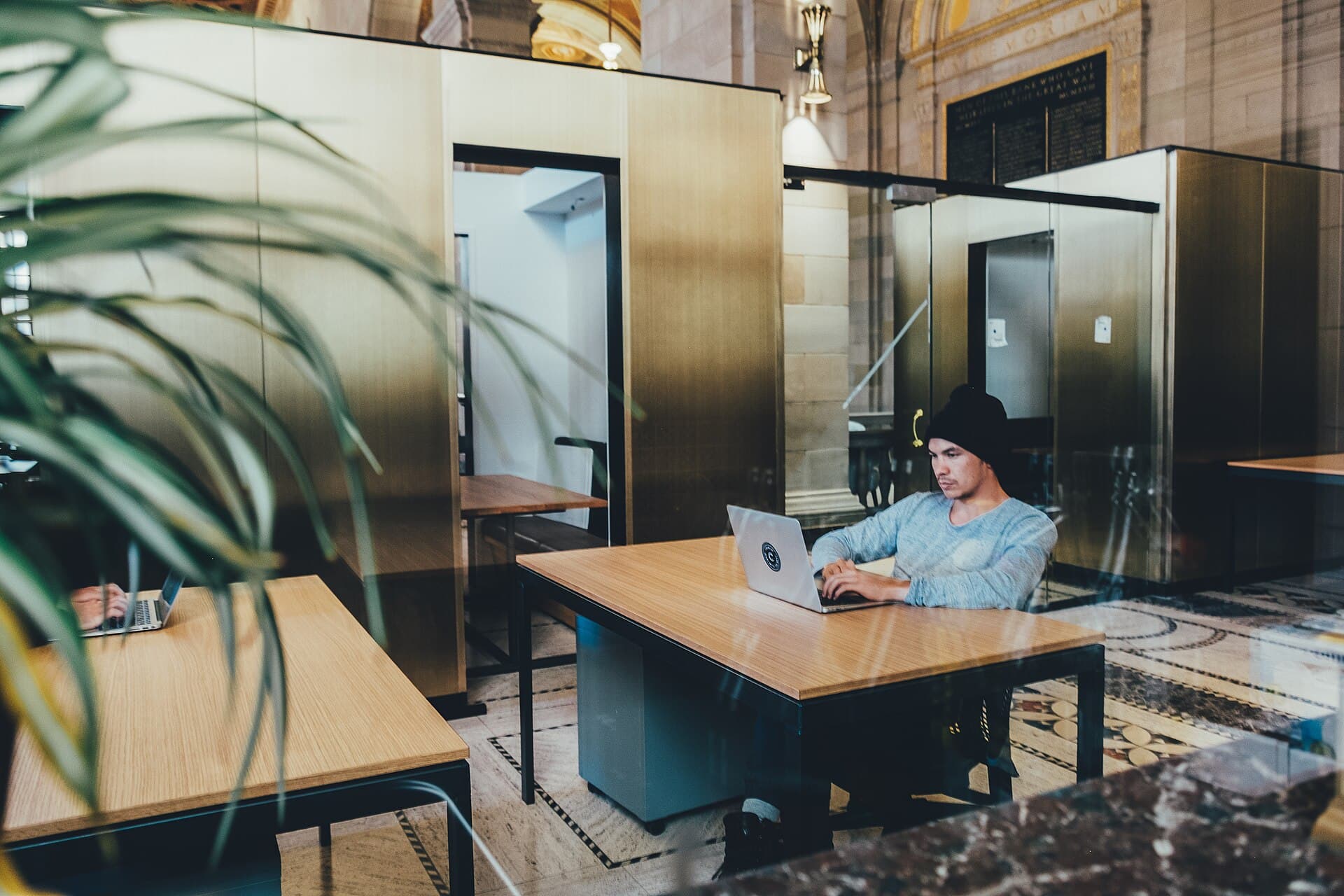 Quiet open office with desks and a person working on a laptop