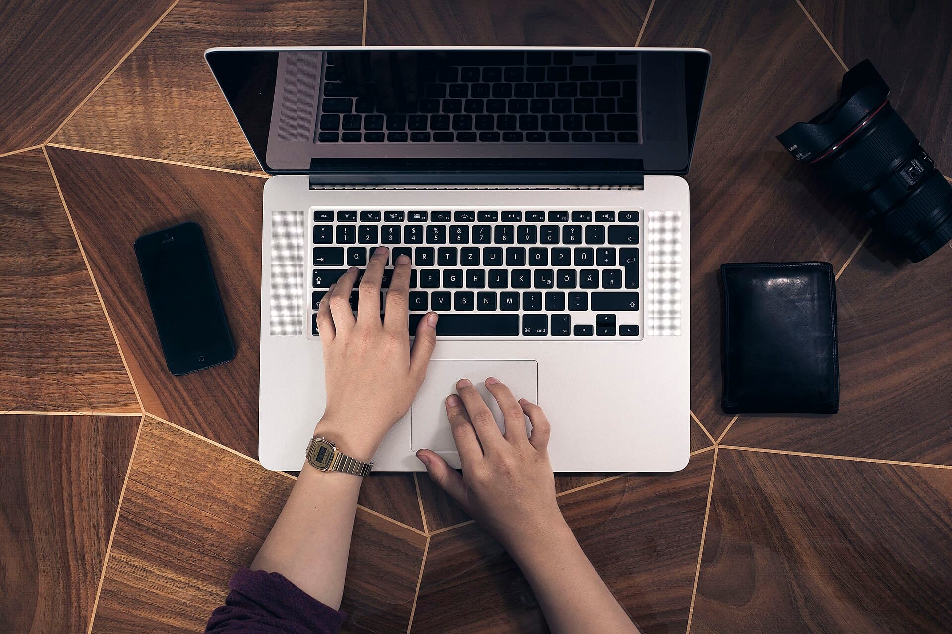 Hands typing on a laptop on a wooden desk